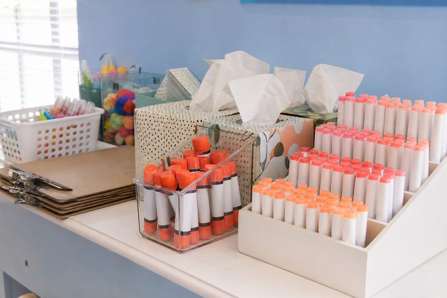 Classroom supplies grouped on a white counter beside a clipboard in bright daylight